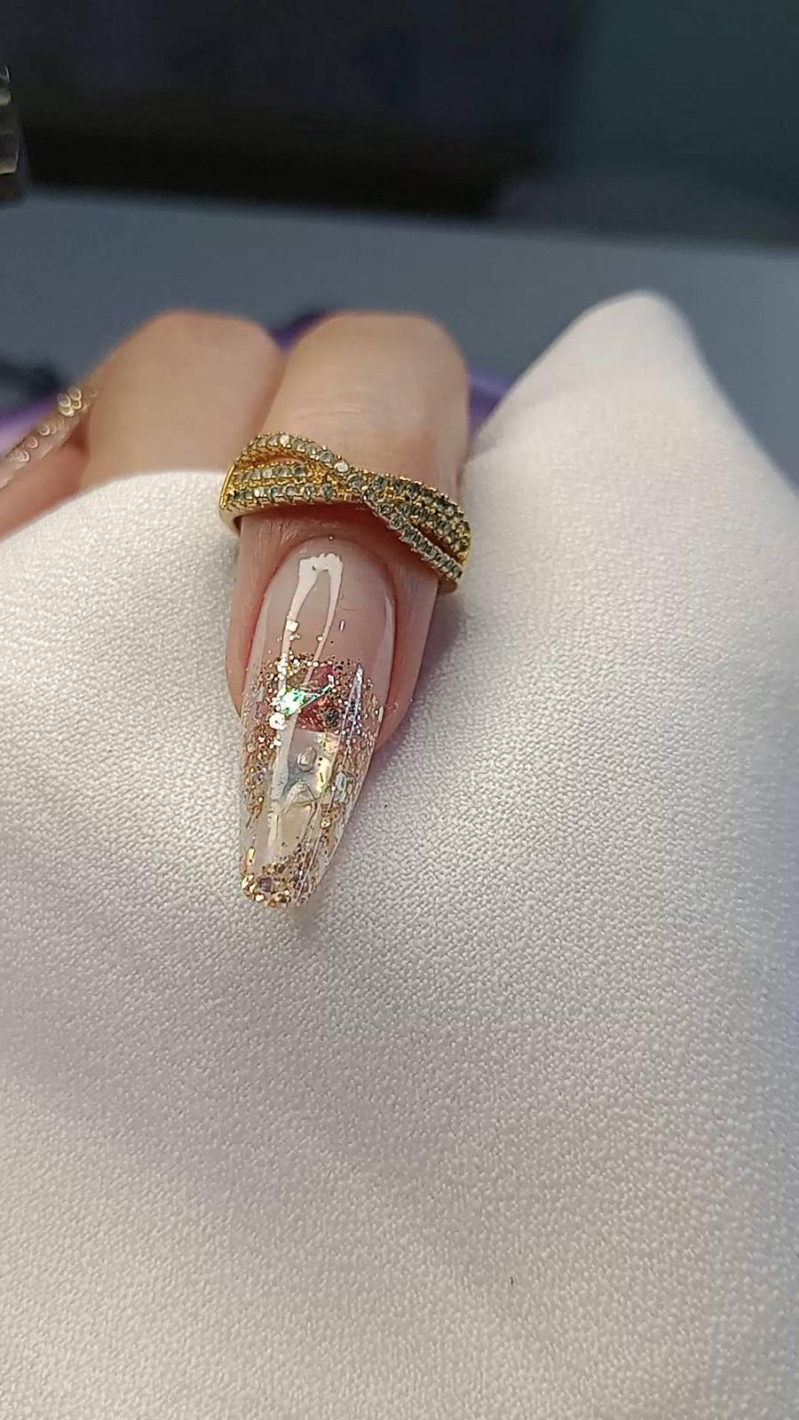 Alongamento de unhas com glitter dourado e anel, acabamento glam